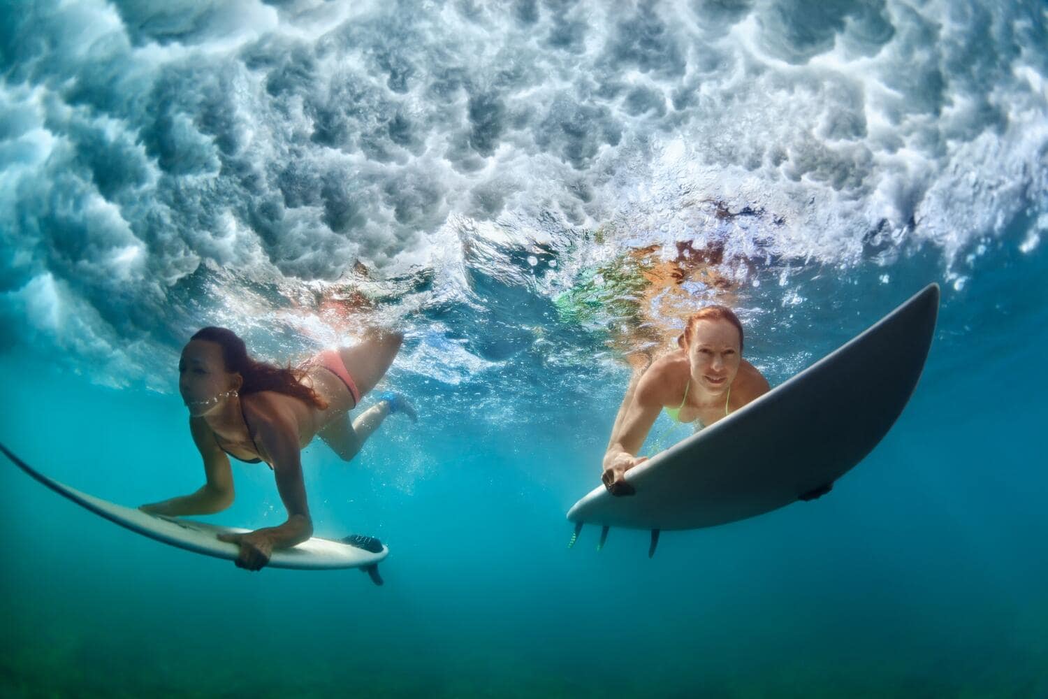 Surfer women with surf board dive underwater under breaking big wave Surfer women with surf board dive underwater under breaking big wave