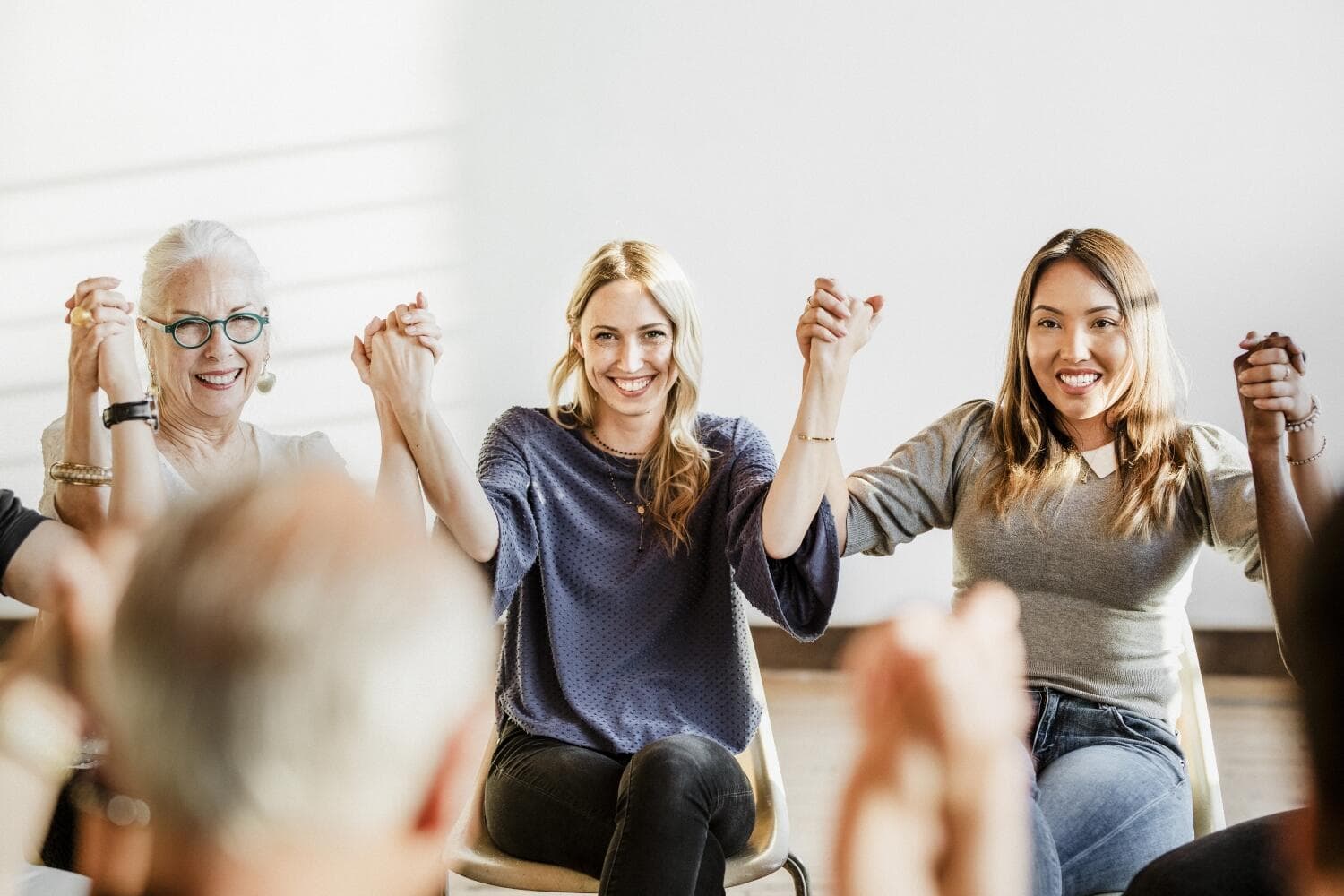 smiling people while holding hands during group therapy - Maui Recovery