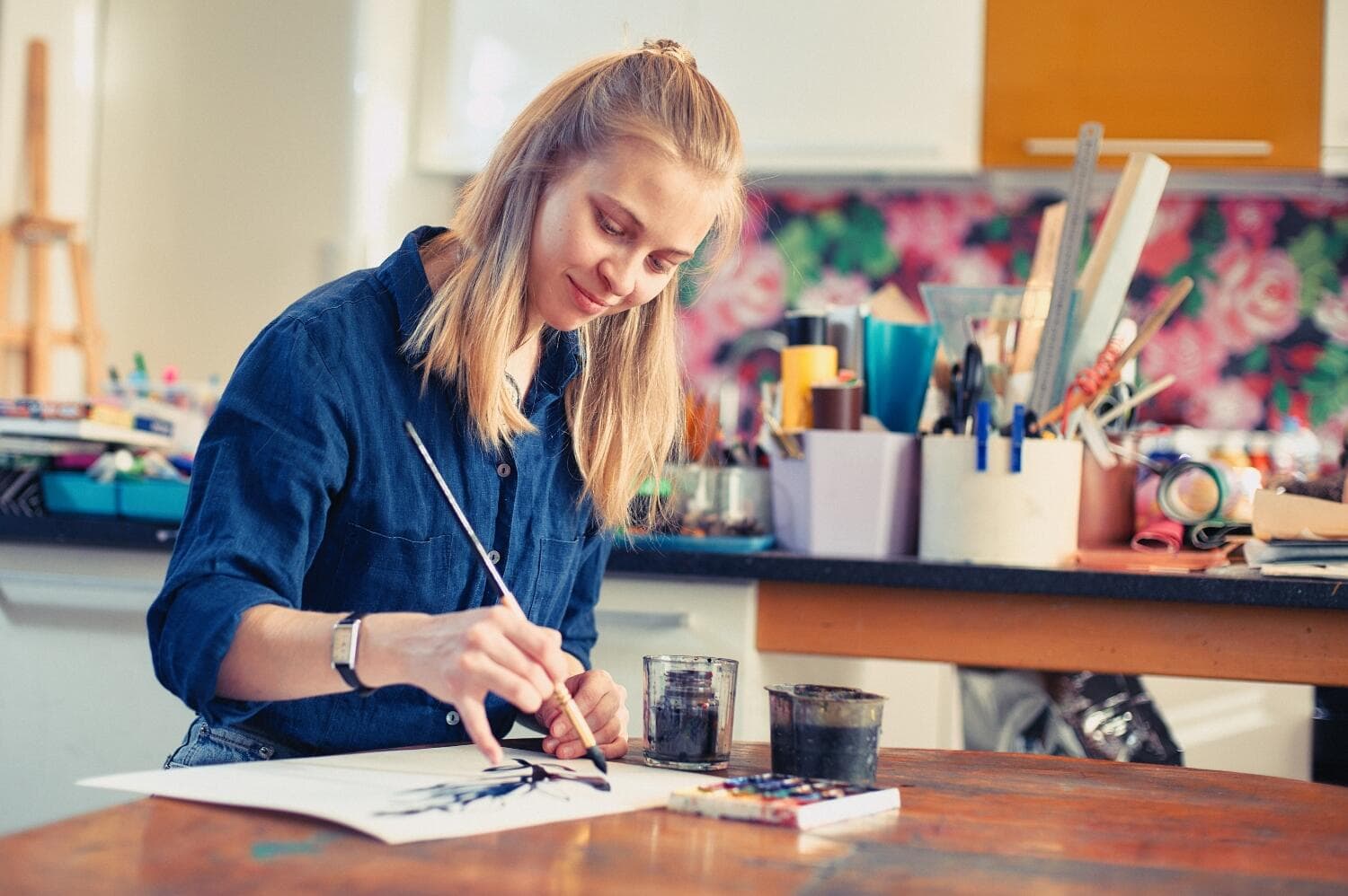 Young Woman Artist Working On Painting In Studio. Selective focus on foreground - Maui Recovery