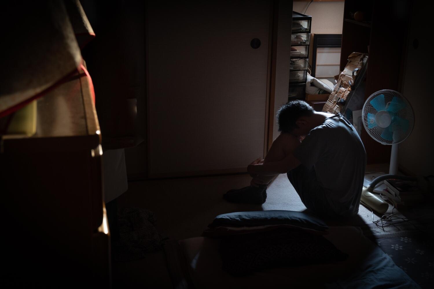 depressed man sitting alone in a dark room depressed man sitting alone in a dark room